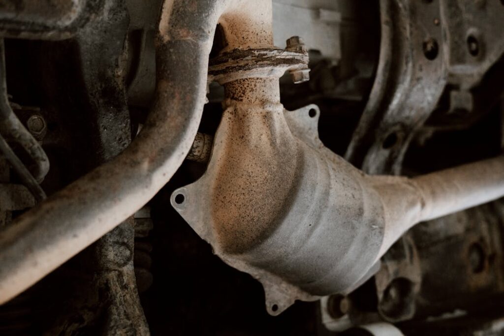 Detailed close-up of rusted exhaust system parts under a vehicle.